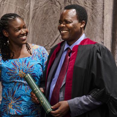 woman smiles at man holding diploma