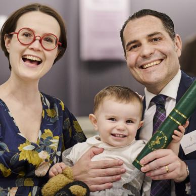 woman and man hold smiling baby and diploma