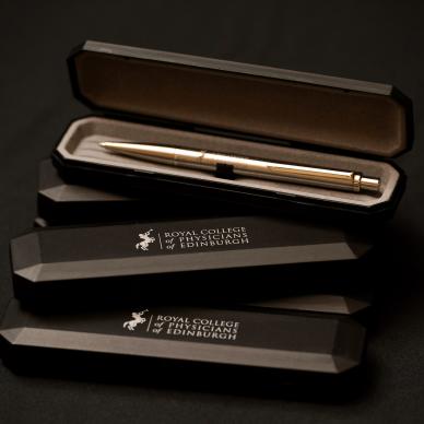 Photo of Classic novara chrome with engraved RCPE logo rollerball pen, with College branded presentation case.